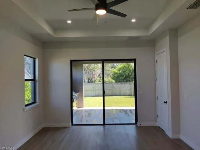Unfurnished room featuring a raised ceiling, dark wood-style flooring, a ceiling fan, and recessed lighting