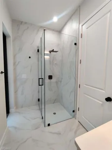 Full bath with marble tiled floors, a marble finish shower, recessed lighting, and vanity