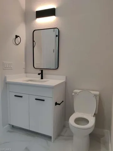 Half bathroom with light marble finish floors and vanity