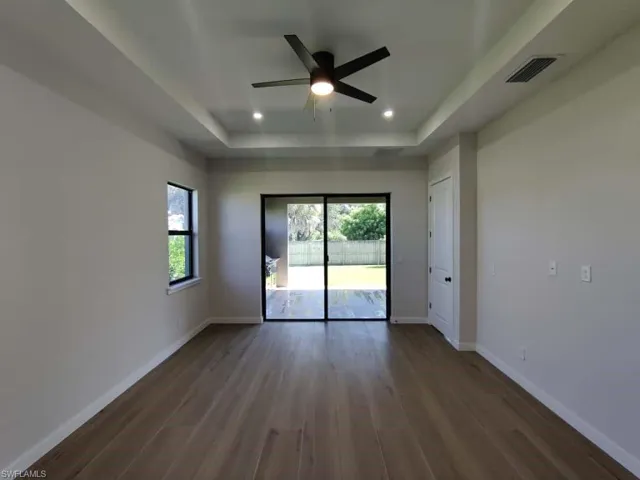 Spare room with dark wood finished floors, a tray ceiling, recessed lighting, and a ceiling fan