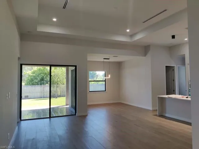 Empty room featuring a raised ceiling, light wood-style flooring, recessed lighting, and a chandelier