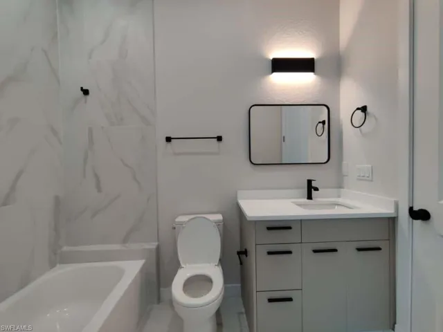Full bathroom with vanity and a combined bath / shower with marble appearance