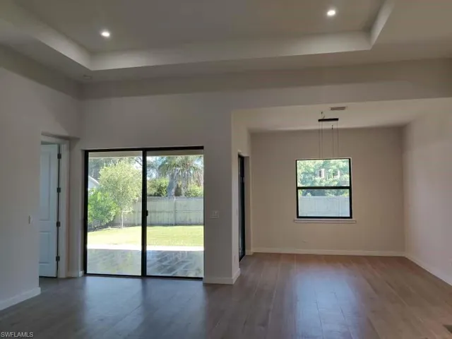 Unfurnished living room featuring a tray ceiling, dark wood-style flooring, and recessed lighting