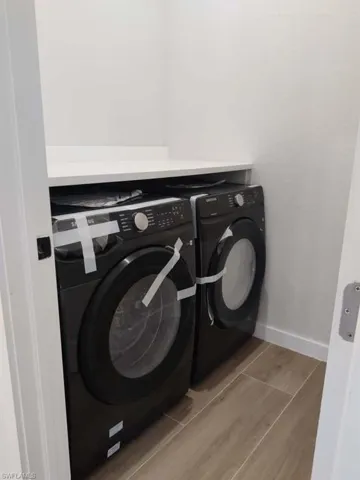 Laundry room featuring washing machine and dryer and wood finish floors