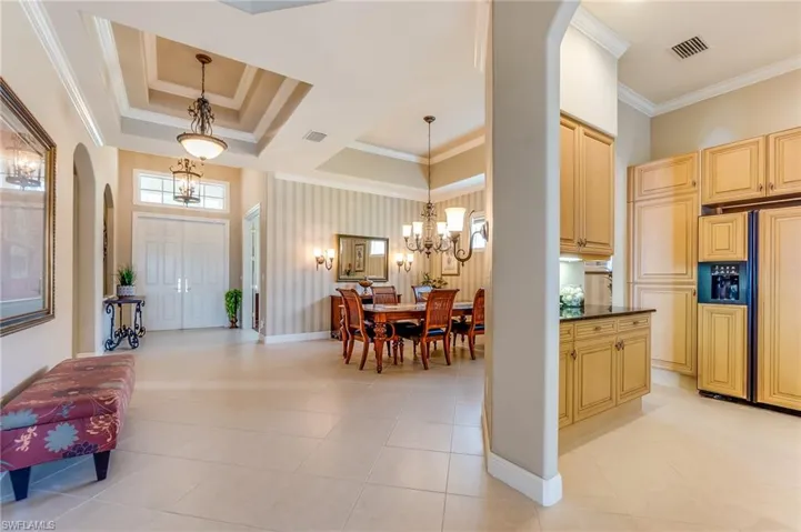 Kitchen featuring paneled fridge, ornamental molding, decorative light fixtures, and light tile patterned floors
