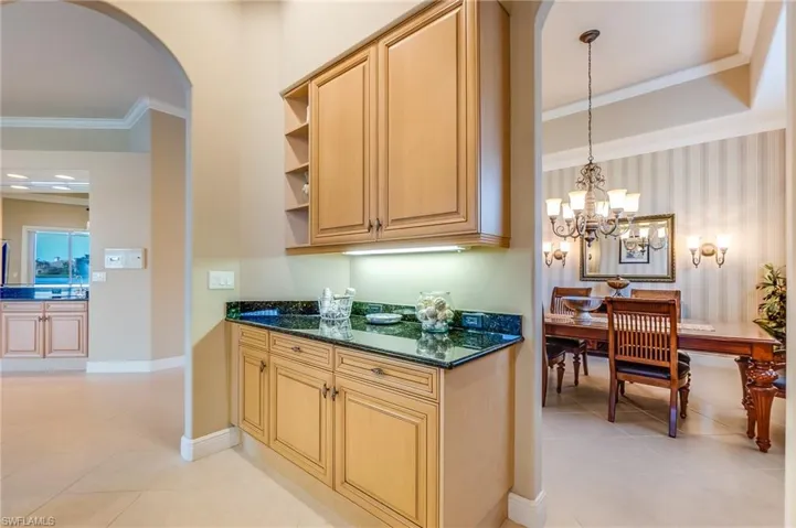 Kitchen featuring a notable chandelier, pendant lighting, light tile patterned floors, and dark stone counters