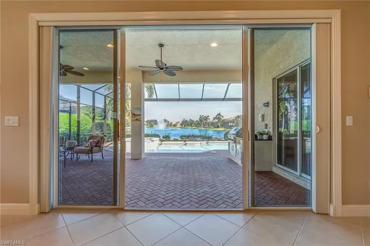 Entryway with a textured ceiling, light tile patterned flooring, a water view, and ceiling fan
