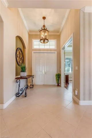 Tiled entryway with an inviting chandelier and ornamental molding