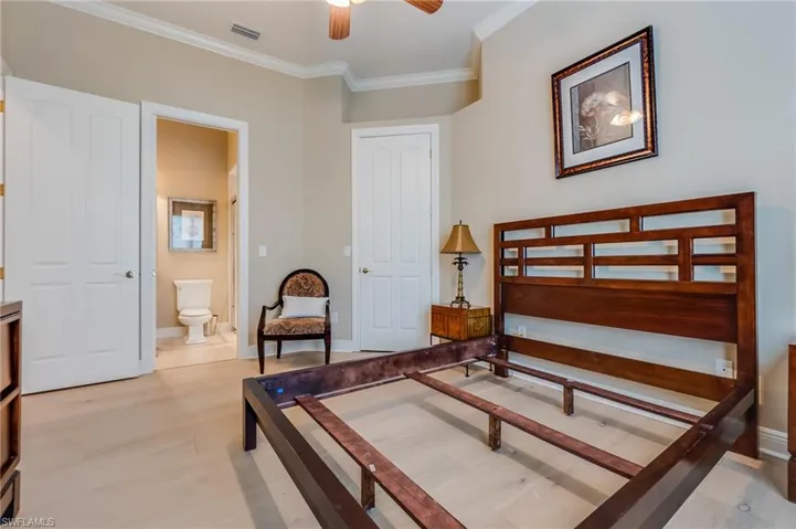 Bedroom featuring crown molding, light hardwood / wood-style flooring, ensuite bathroom, and ceiling fan