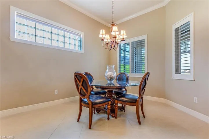 Dining area with ornamental molding, a notable chandelier, and plenty of natural light