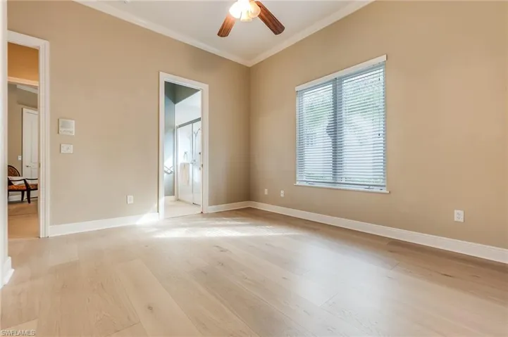 Empty room with crown molding, light wood-type flooring, and ceiling fan