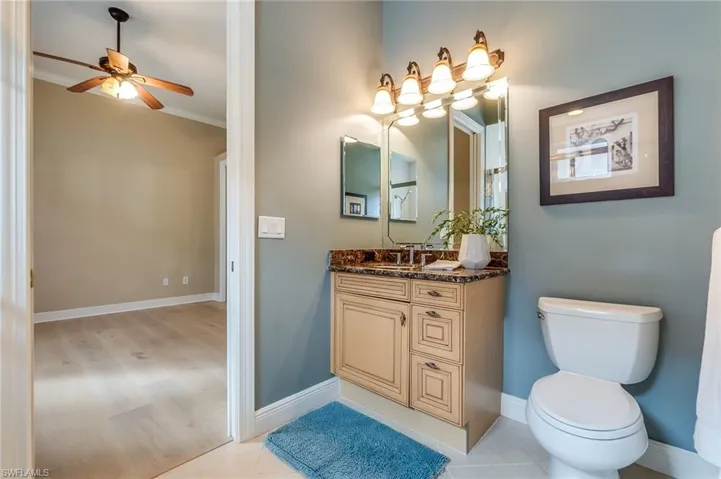 Bathroom featuring toilet, tile patterned flooring, crown molding, vanity, and ceiling fan