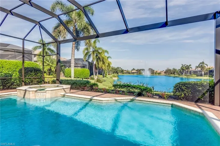 View of pool featuring an in ground hot tub, a water view, and glass enclosure
