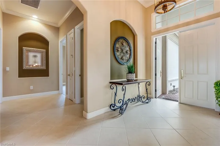 Tiled foyer entrance featuring crown molding
