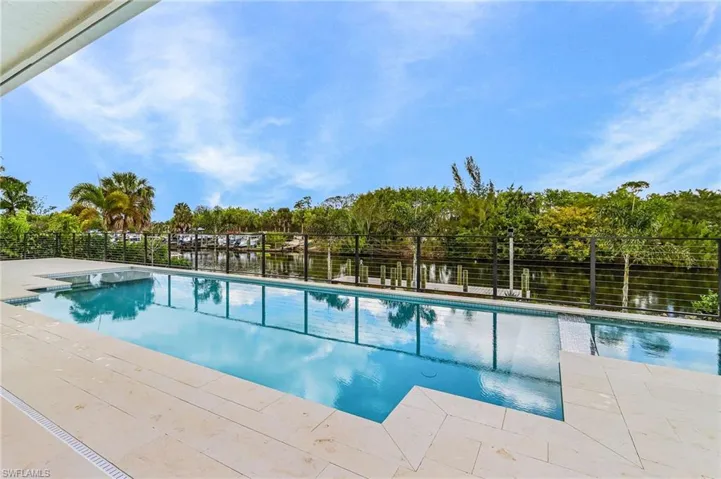 View of pool with patio surround and view of wooded area