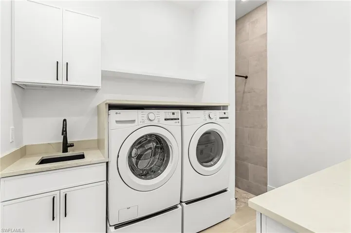 Laundry area with washing machine and dryer, cabinet space, and light tile patterned flooring