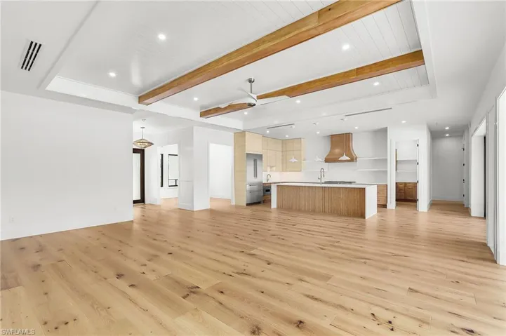 Unfurnished living room featuring recessed lighting, a ceiling fan, beamed ceiling, and light wood-style flooring