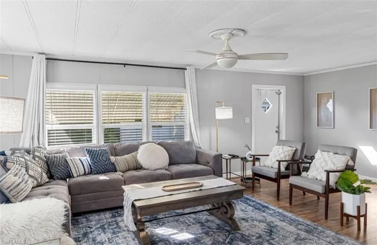 Living room featuring dark wood-type flooring, a textured ceiling, and a ceiling fan