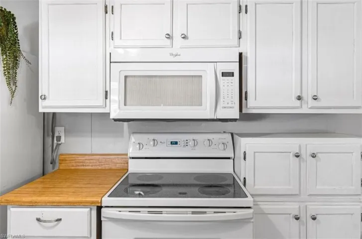 Kitchen featuring white appliances, light countertops, and white cabinets
