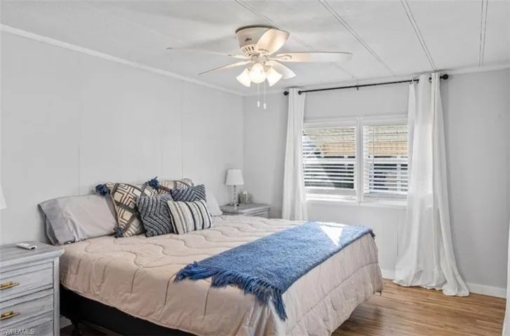 Bedroom with crown molding, wood finished floors, and ceiling fan