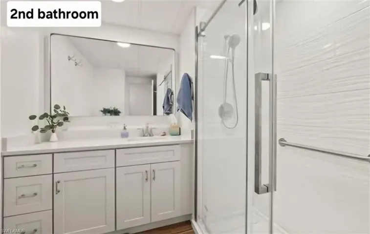 Full bath featuring a stall shower, vanity, and dark wood-style floors