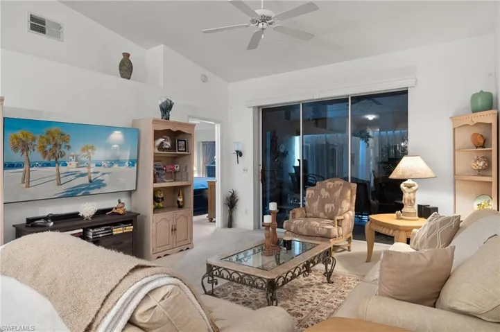 Carpeted living room with vaulted ceiling and ceiling fan
