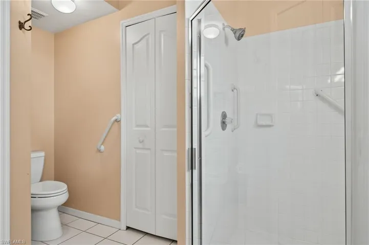 Bathroom featuring tile patterned flooring, a shower with door, and toilet
