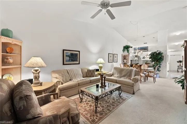 Living room with light carpet, vaulted ceiling, and ceiling fan