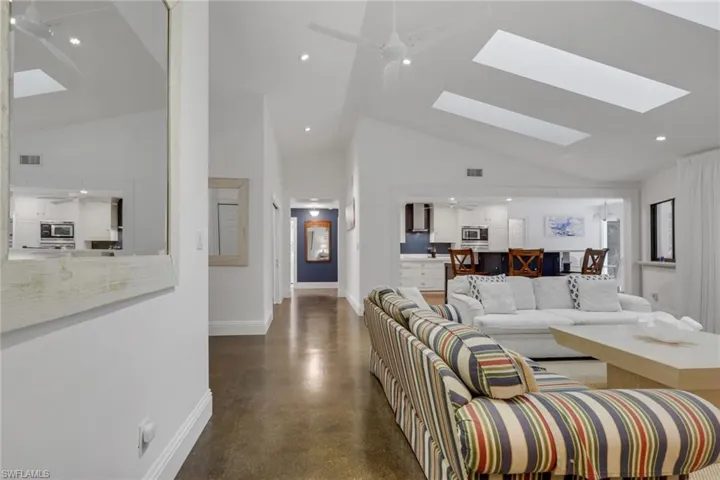 Living room with ceiling fan, polished concrete floors, vaulted ceiling, recessed lighting, and a skylights