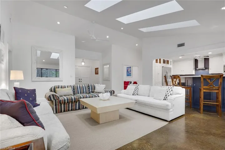 Living area featuring ceiling fan, concrete flooring, recessed lighting, lofted ceiling, and a skylight