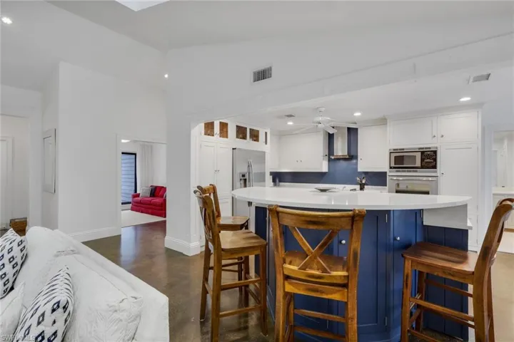 Kitchen featuring polished concrete flooring, a ceiling fan, a kitchen bar, stainless steel appliances, and recessed lighting