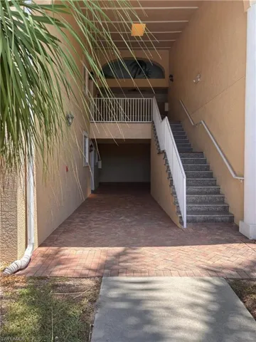 Entryway featuring a brick paver drive, concrete walkway, and exterior staircase with white railings