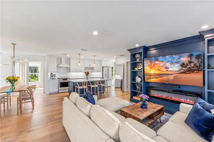 Living room with built in entertainment center, electric fireplace, light hardwood floors