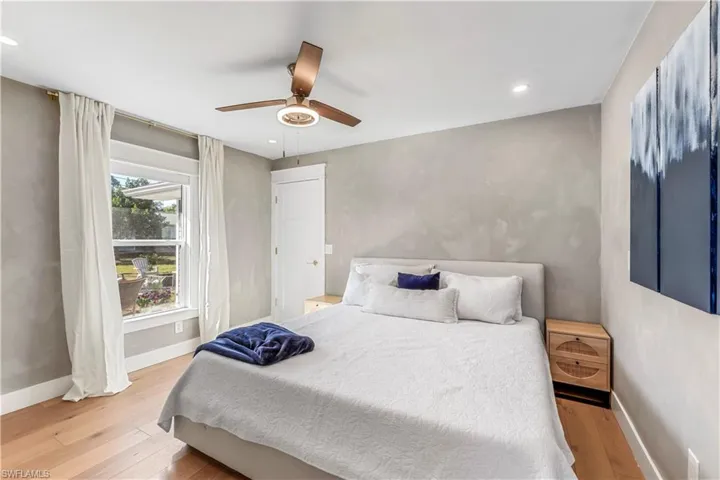 Bedroom with light hardwood floors and ceiling fan - overlooks backyard.