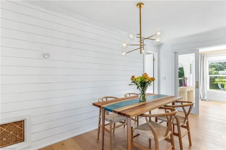 Dining area with shiplap accent wall, light hardwood flooring.