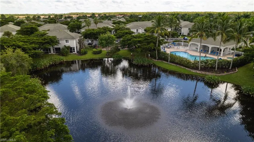 Community features a central water body with a fountain, surrounded by lush landscaping and residential structures