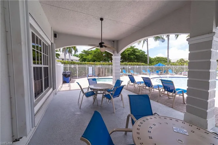 Covered outdoor patio with a ceiling fan, arched architectural elements, and direct access to a fenced swimming pool area