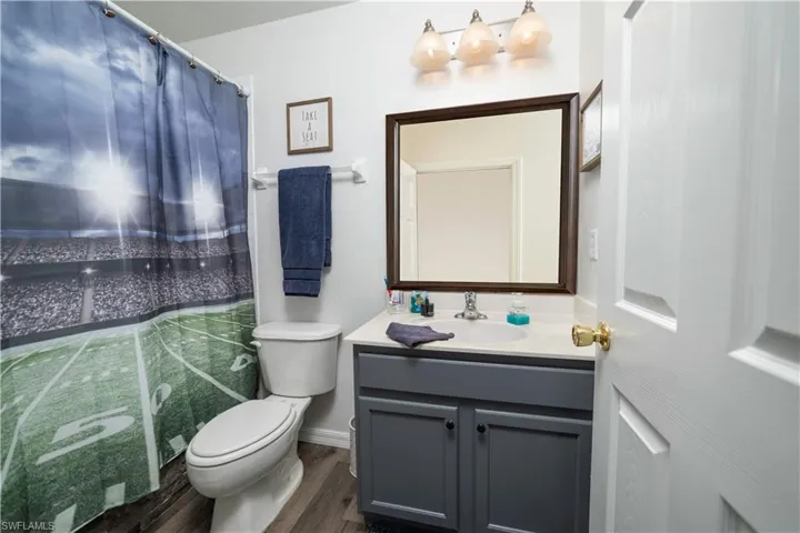 Vanity with a gray cabinet, single basin sink, and a framed mirror