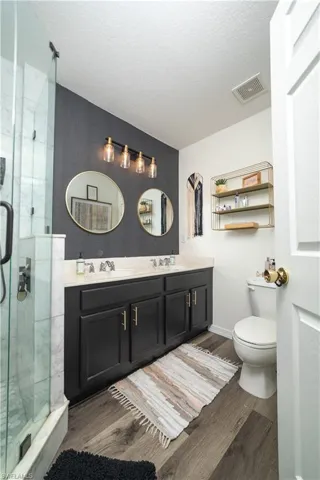 Dual sink vanity with dark cabinetry, light-colored countertop, and gold-tone hardware