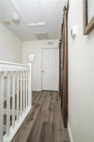 Wood-finish flooring, white paneled door, and a rustic wood-finish barn door