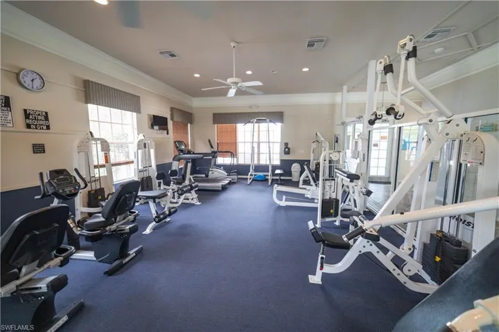 Fitness area featuring multiple exercise machines, carpet flooring, a ceiling fan, and large windows