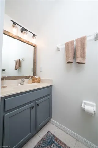 Vanity with a light-colored countertop, recessed sink, and dark gray cabinetry