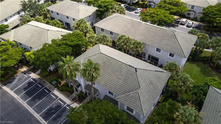 Aerial perspective showcasing multiple units with tile roofing, mature palm trees, and designated parking areas
