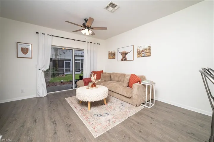 Wood-finish flooring throughout, ceiling fan with integrated lighting, and sliding glass doors