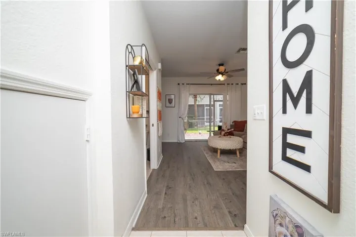 Wood-finish flooring throughout, ceiling fan with integrated lighting, sliding glass doors, private outdoor space with screening, and an architectural shelf