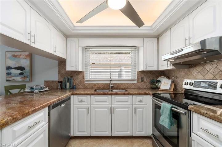 Updated white kitchen features granite counters and updated fan lighting.