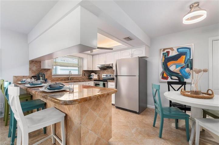 Open kitchen/eat-in counter bar area is light and bright with updated paint and lighting.
