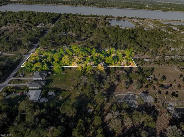 Aerial view of property and surrounding area with property parcel outlined and a nearby body of water
