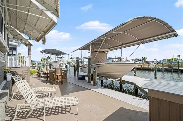 Dock featuring boat lift, a water view, and a patio