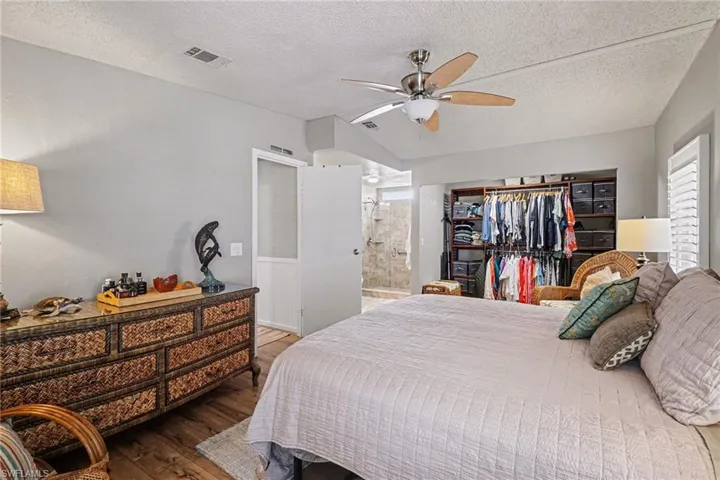 Bedroom with hardwood / wood-style flooring, a textured ceiling, a ceiling fan, and connected bathroom